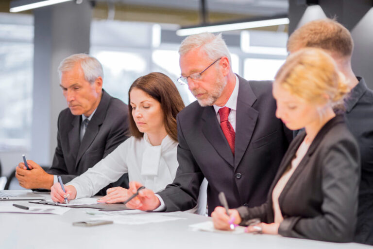 Uomini e donne d'affari in abiti formali che lavorano insieme al tavolo.
